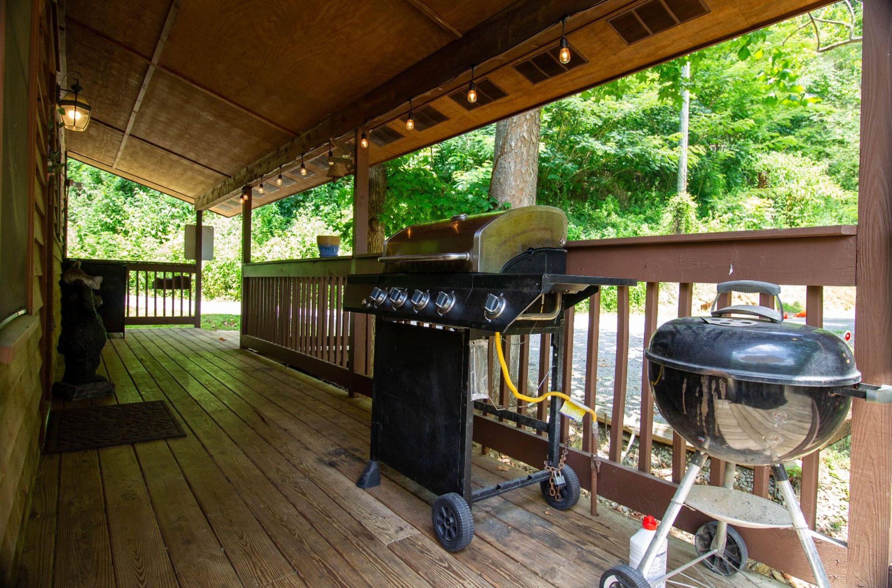 A covered outdoor area with a grill and a barbecue.