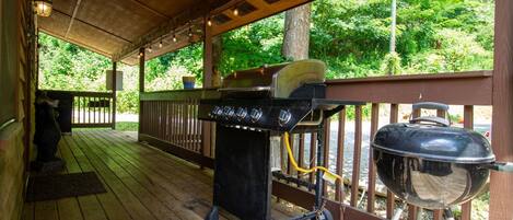 A covered outdoor area with a grill and a barbecue.