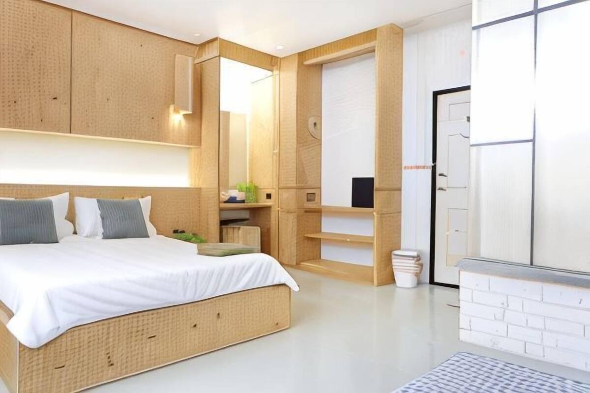 Quarto moderno com cama, estantes embutidas e porta branca.