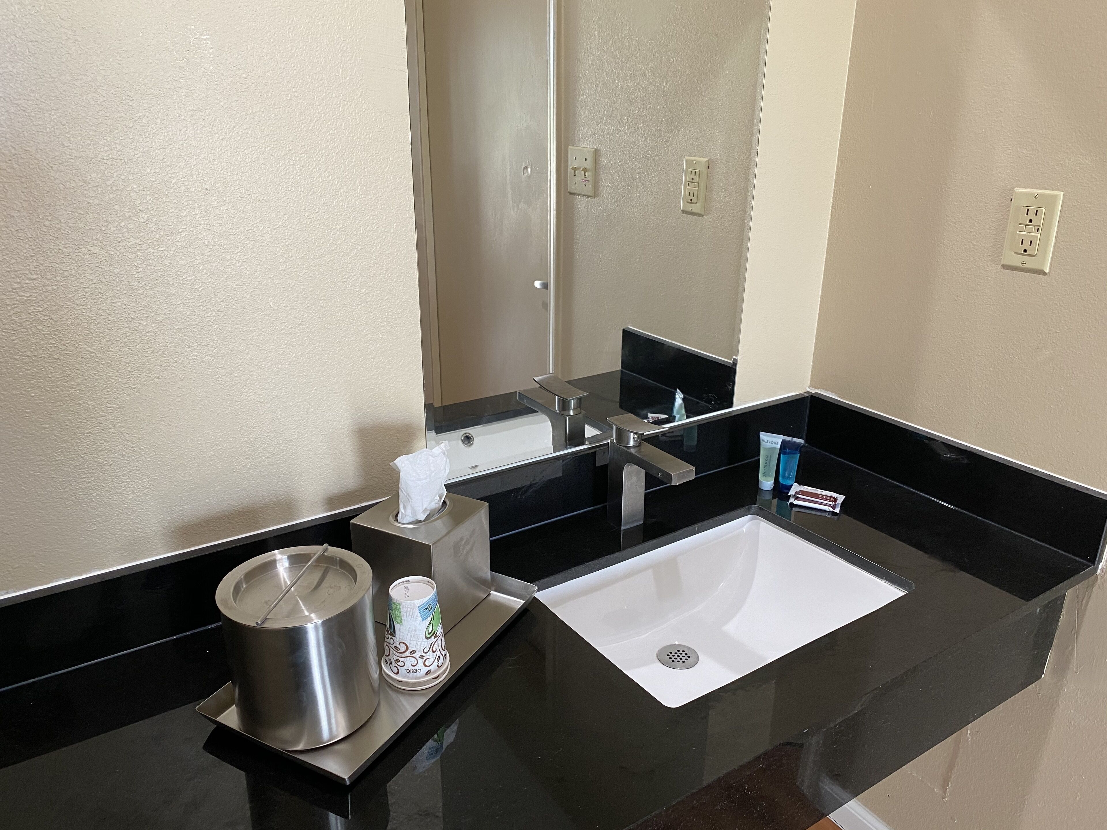 Un baño moderno con encimera negra, lavabo blanco y espejo.