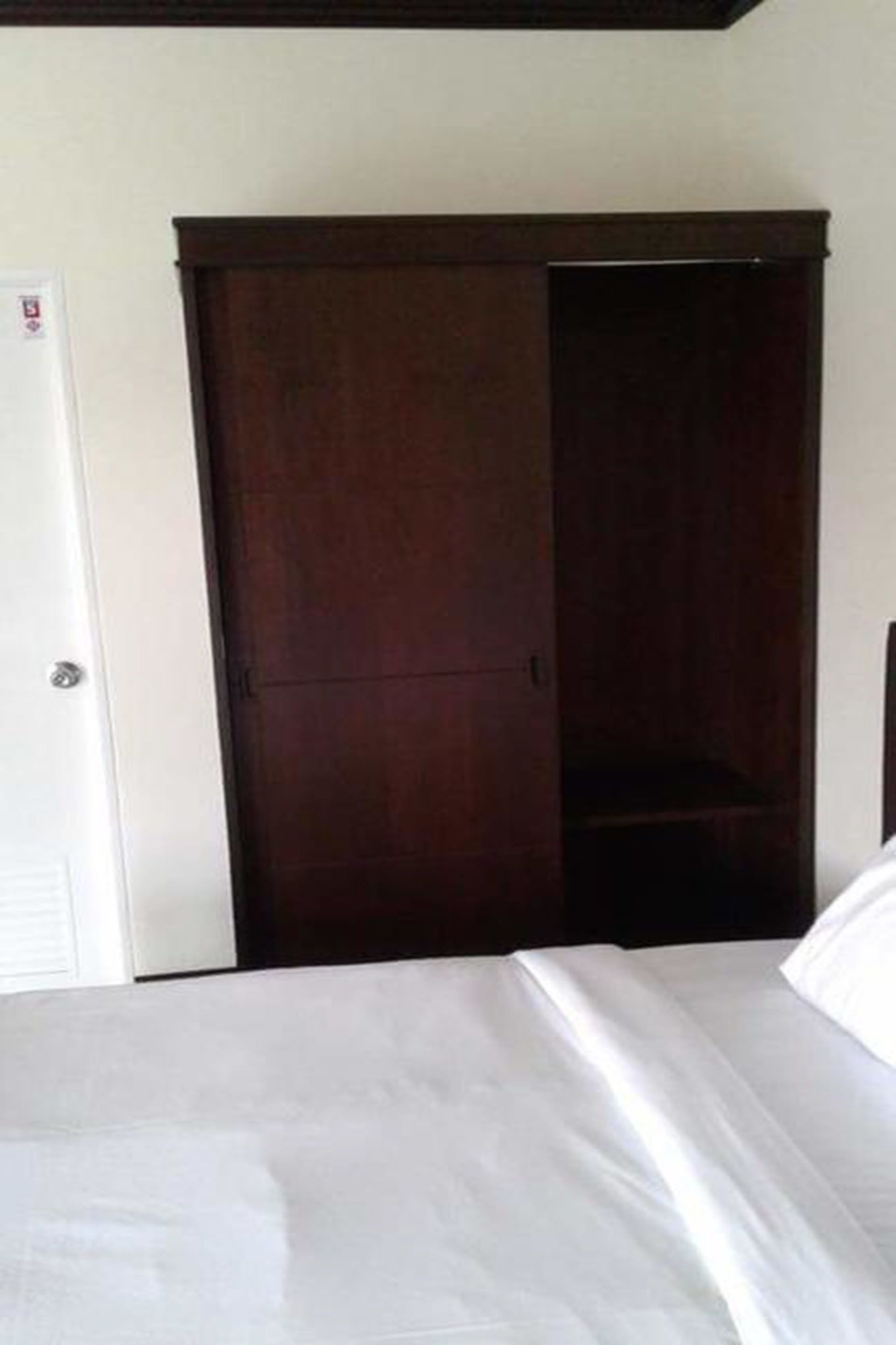 Quarto com cama, guarda-roupa e porta.