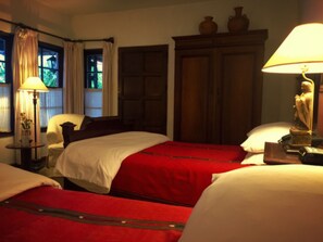 A hotel room with two beds, a wooden wardrobe, a lamp, and a window with curtains. - Casa Capuchinas (Antigua Guatemala)
