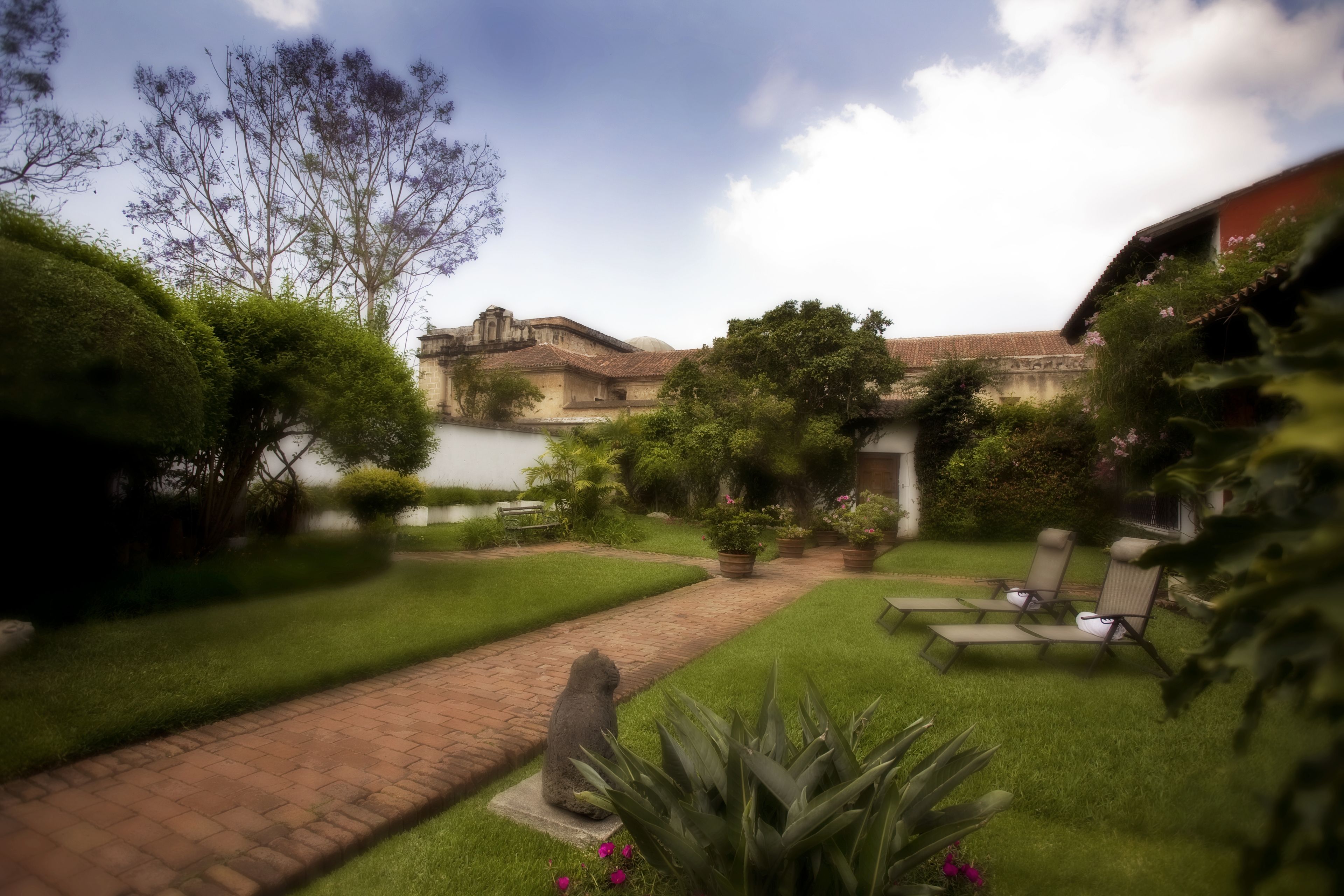 A courtyard with a paved pathway, green lawns, and outdoor seating.