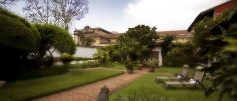 Un patio con sendero adoquinado, césped verde y mobiliario de exterior.