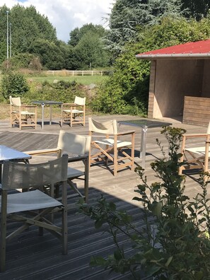 An outdoor patio with wooden furniture and a pool. - Le Salin (Brehal)