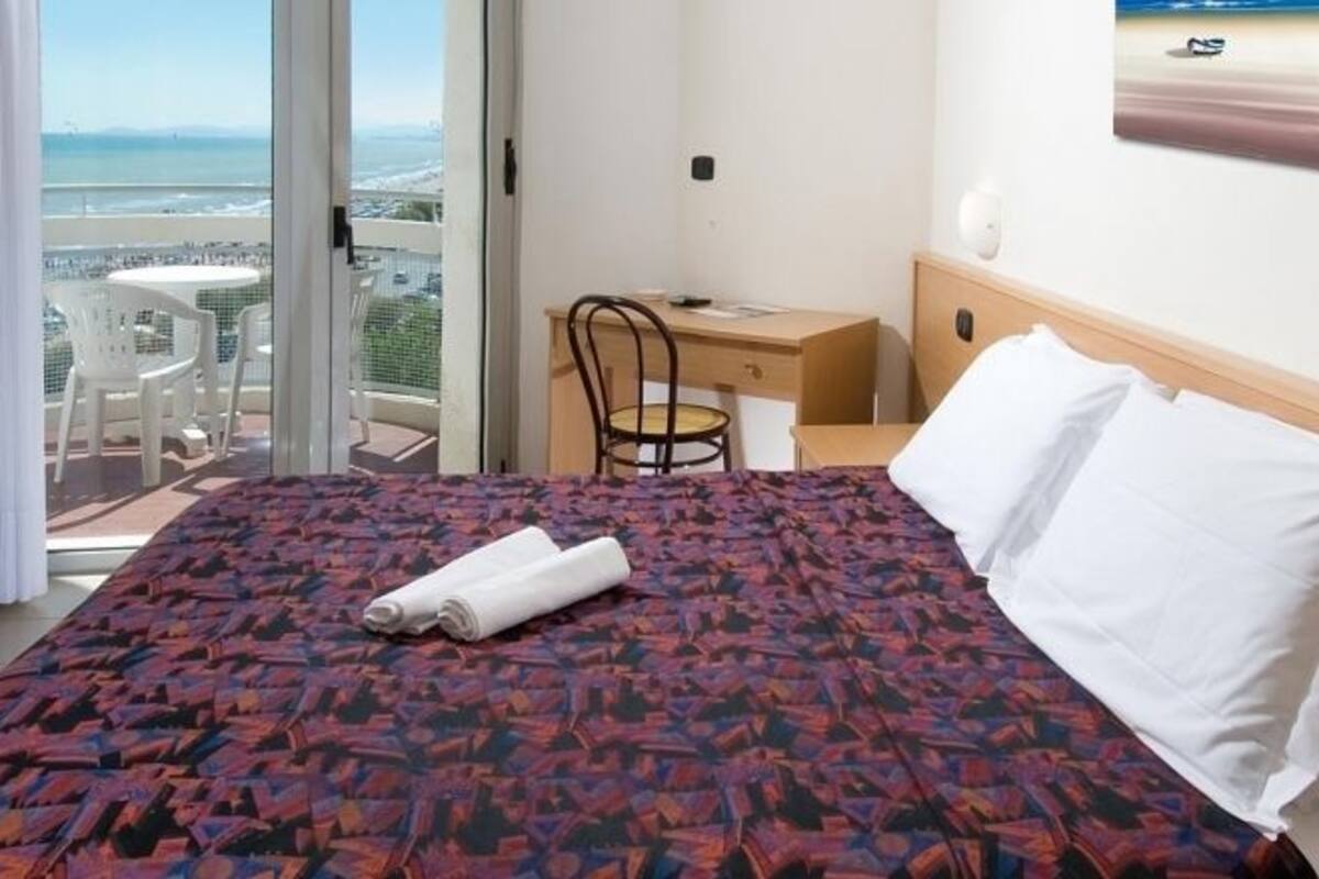 Une chambre d’hôtel avec un lit, un bureau, une chaise et une vue sur la ville.