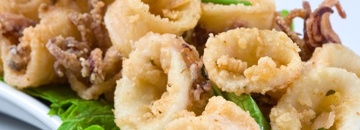 A plate of fried calamari with a green garnish.