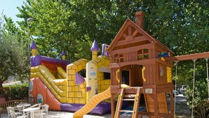 Een houten speelhuisje met een glijbaan en een klimladder.