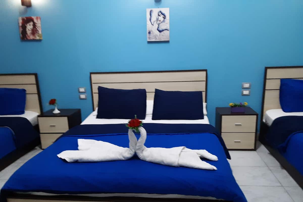 Ein Hotelzimmer mit einem großen Bett, zwei Nachttischen und einer blauen Wand.