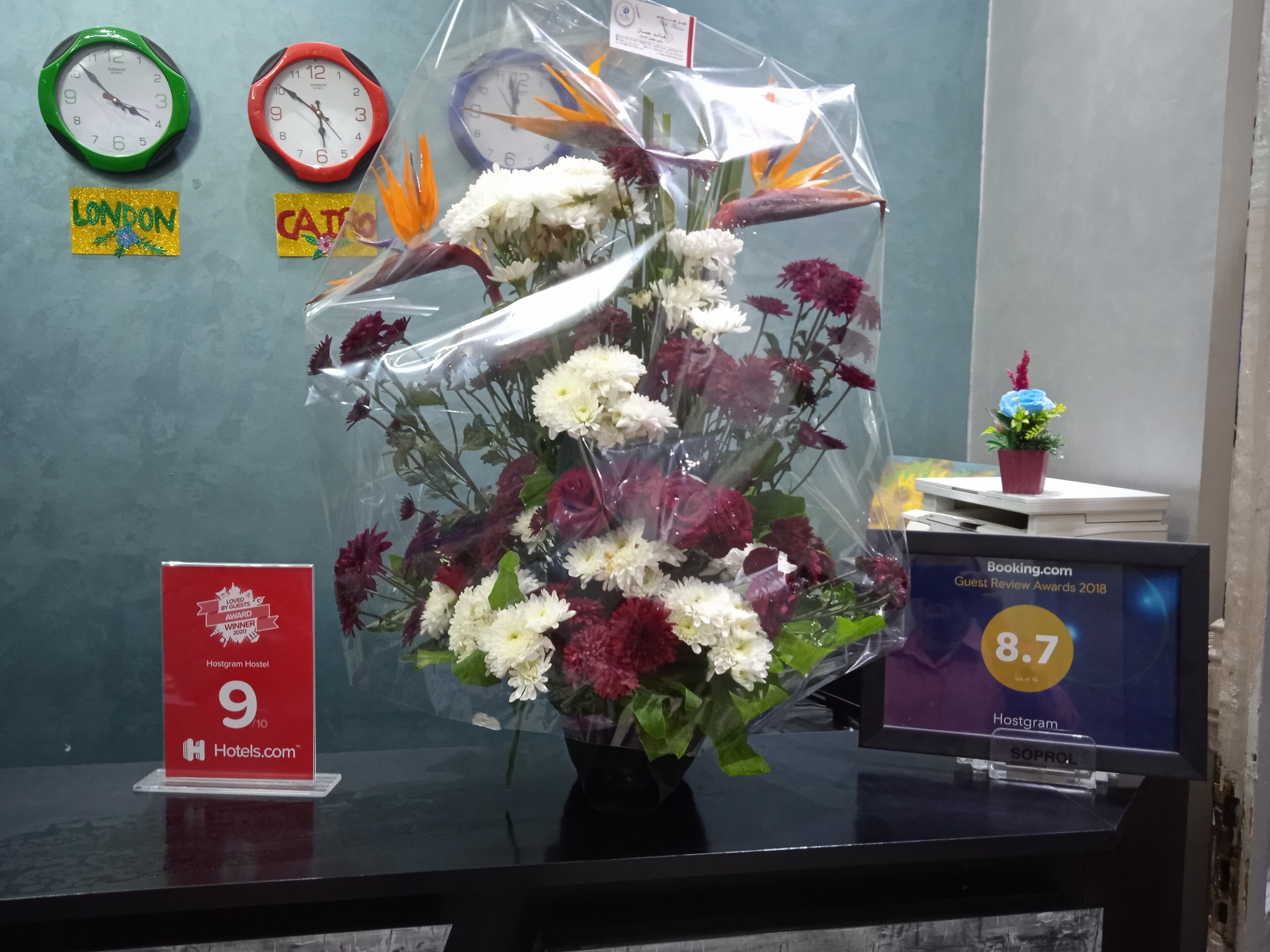 Un bureau orné d’un bouquet de fleurs, d’une horloge, d’un trophée encadré et d’un panneau indiquant une évaluation.