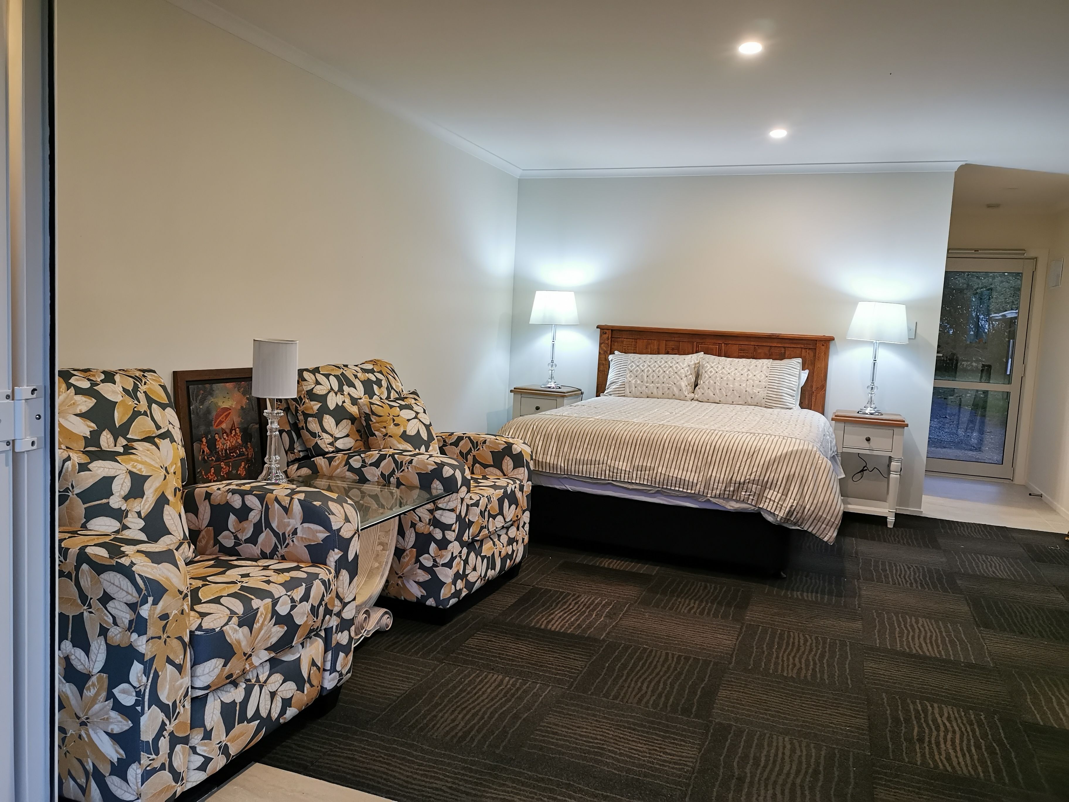 A bedroom with a bed, two nightstands, a chair, and a window.