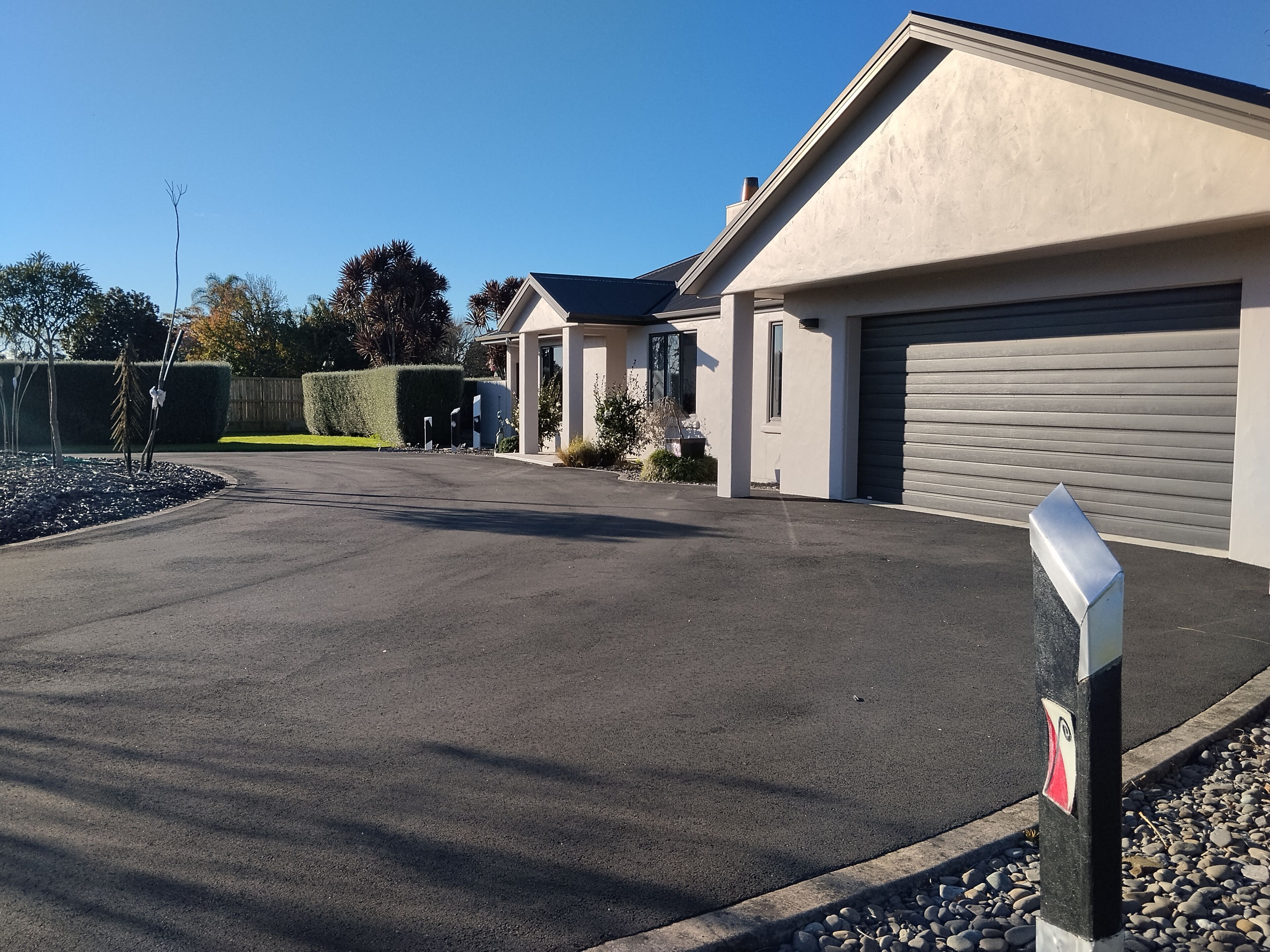 A modern building with a garage, a driveway, and a well-maintained lawn.
