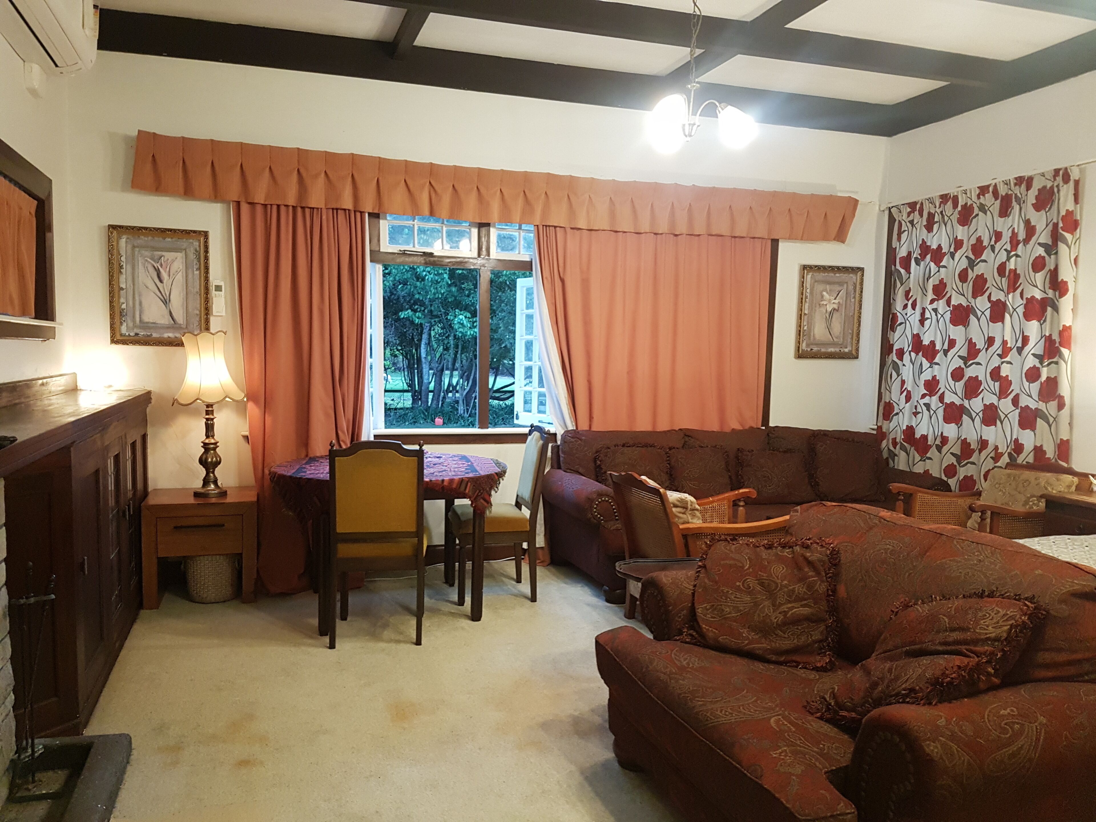 Una sala de estar acogedora con un sofá, sillas, una mesa y un ventanal con cortinas.