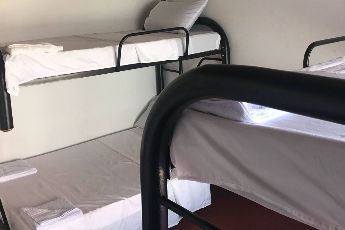 Un dormitorio con literas, un ventilador de techo y un equipo de aire acondicionado.