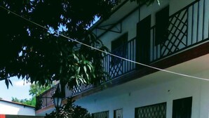 Un edificio con una zona esterna coperta, una piscina e un giardino con diverse piante.