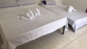 Una camera d'albergo con due letti, ognuno con copripiumino e cuscini bianchi.