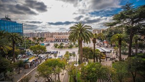 A cityscape with a prominent roundabout, palm trees, and a mix of modern and historic buildings. - Travel B&B (Bari)