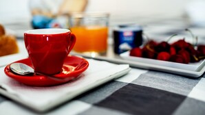 A breakfast setting with a red cup, a glass of orange juice, and a plate of cherries. - Travel B&B (Bari)