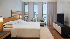 Habitación de hotel moderna con una cama grande, televisión, escritorio y vistas a la ciudad.