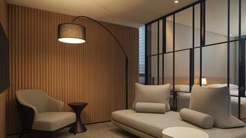A modern living room with a sofa, armchairs, a small side table, and a floor lamp.