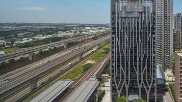 Un immeuble moderne de grande hauteur, doté d’une façade originale, entouré de nombreuses autoroutes et d’espaces verts.