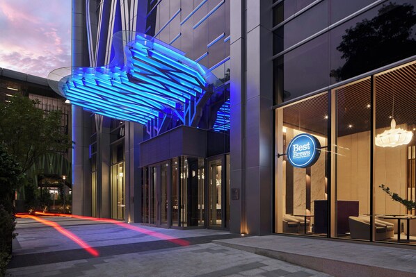 Een modern gebouw met een glazen gevel, een blauw verlichte constructie en een bord met de tekst 'Best Brews'.