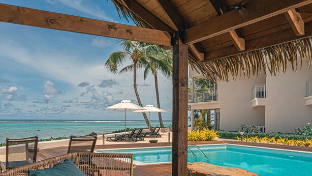 Uma área na piscina com espreguiçadeiras, guarda-sóis e vista para o oceano.