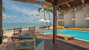 Una piscina al aire libre, sombrillas, sillones reclinables de piscina