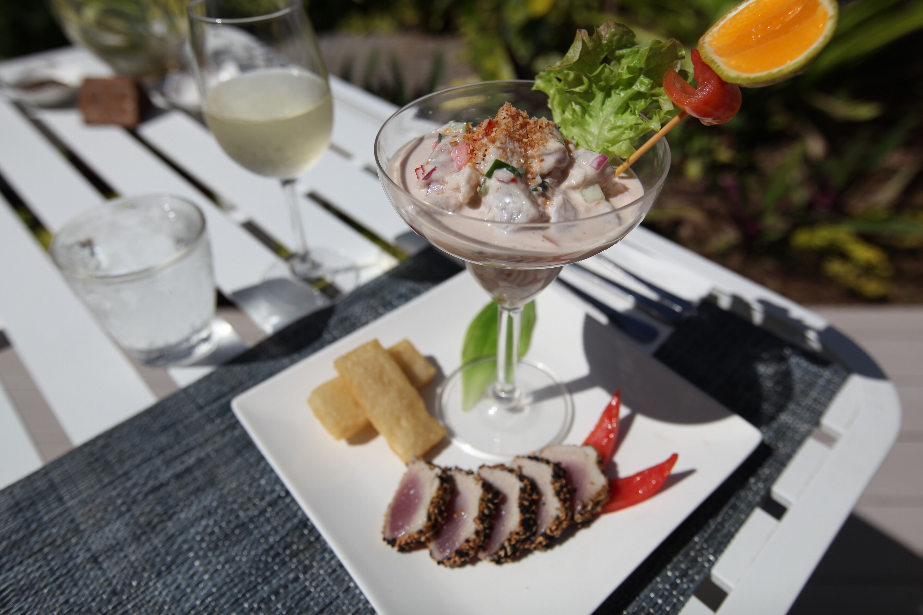 A seafood dish with a glass of white wine on a white table.