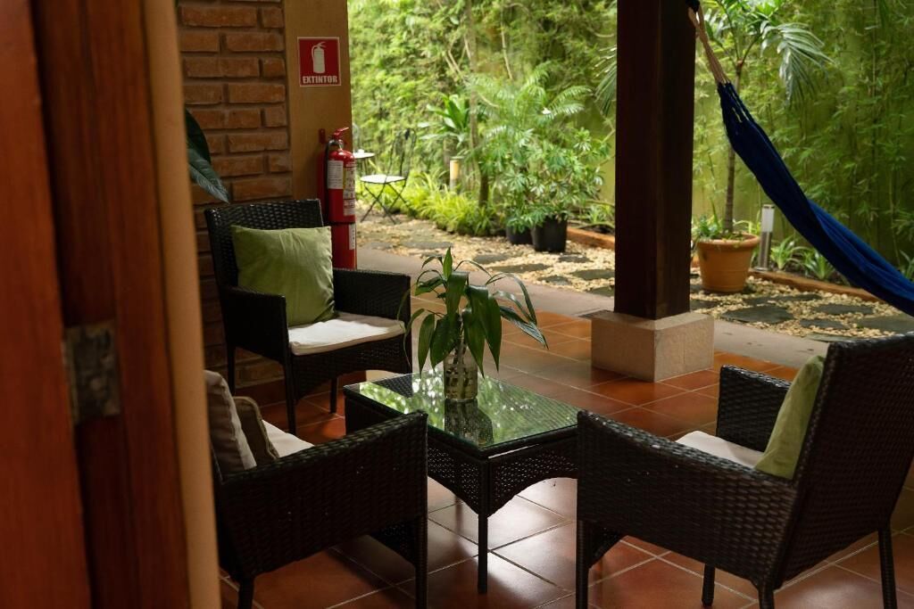 An outdoor seating area with wicker furniture, a glass table, and a fire extinguisher.