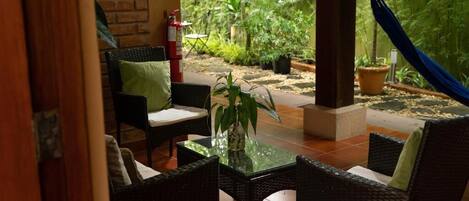An outdoor seating area with wicker furniture, a glass table, and a fire extinguisher.