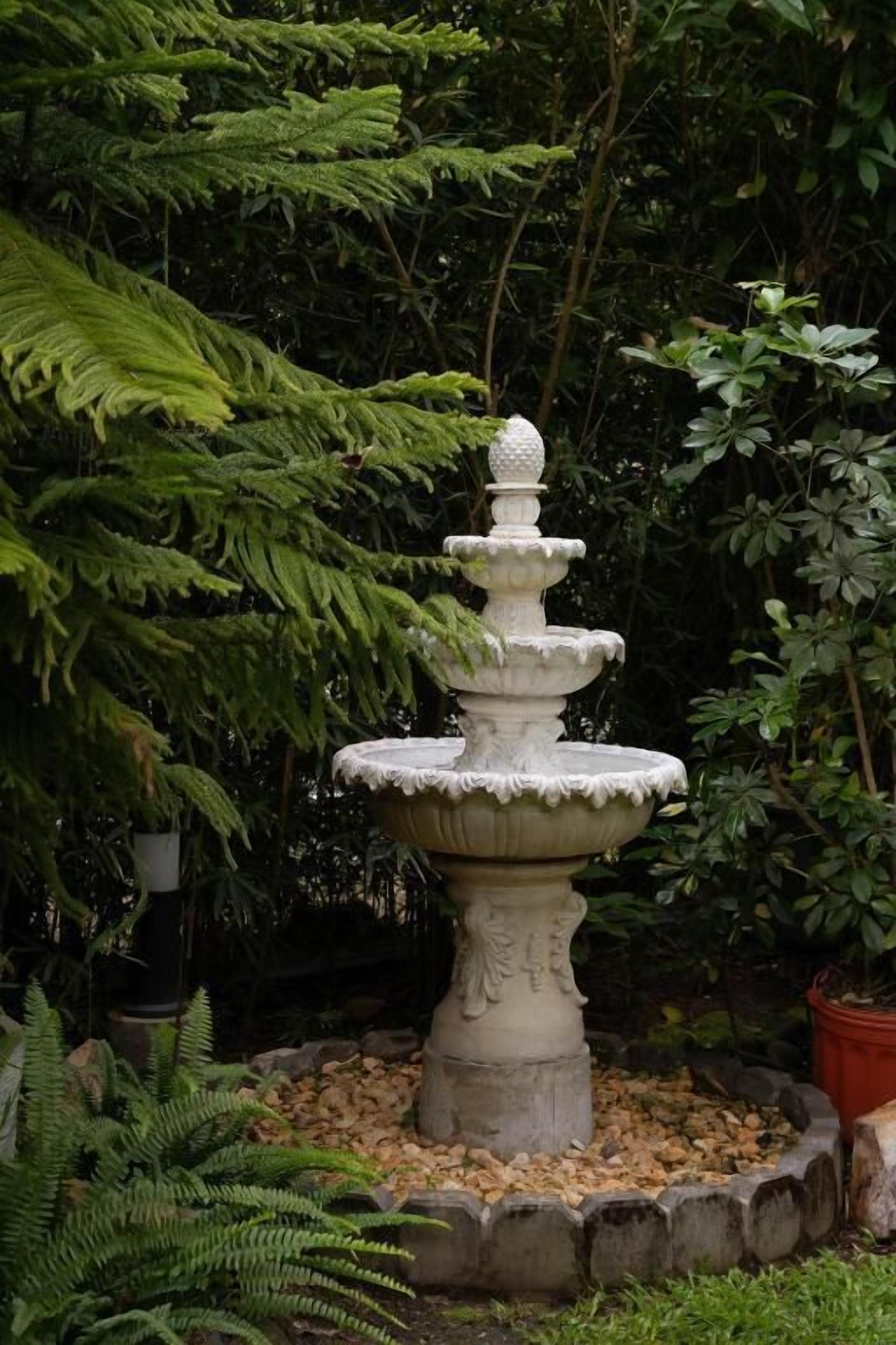 A tiered stone fountain surrounded by greenery.