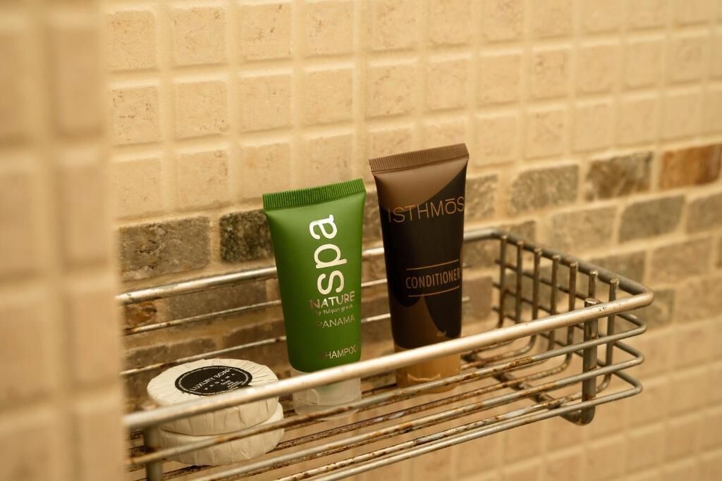A bathroom shelf with a green spa product, a brown conditioner, and a white toiletry item.