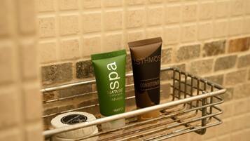 A bathroom shelf with a green spa product, a brown conditioner, and a white toiletry item.
