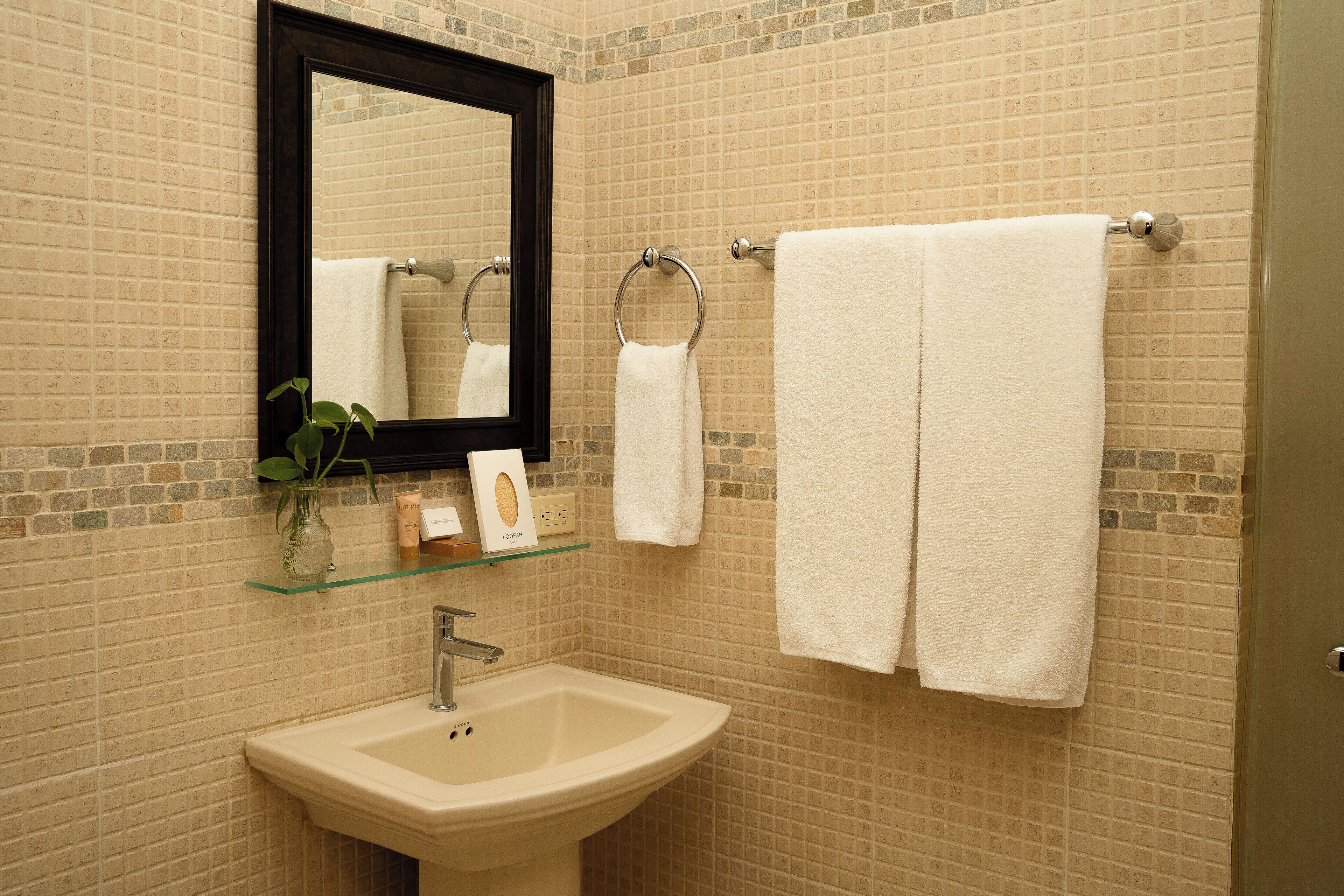 A bathroom with a beige sink, a mirror, and two white towels hanging on a towel rack.