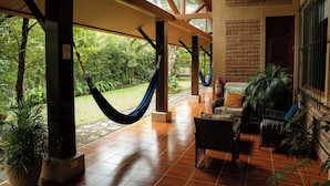 A covered patio area with hammocks, outdoor furniture, and potted plants. - Caracoral Hotel Boutique & Spa (El Valle de Anton)