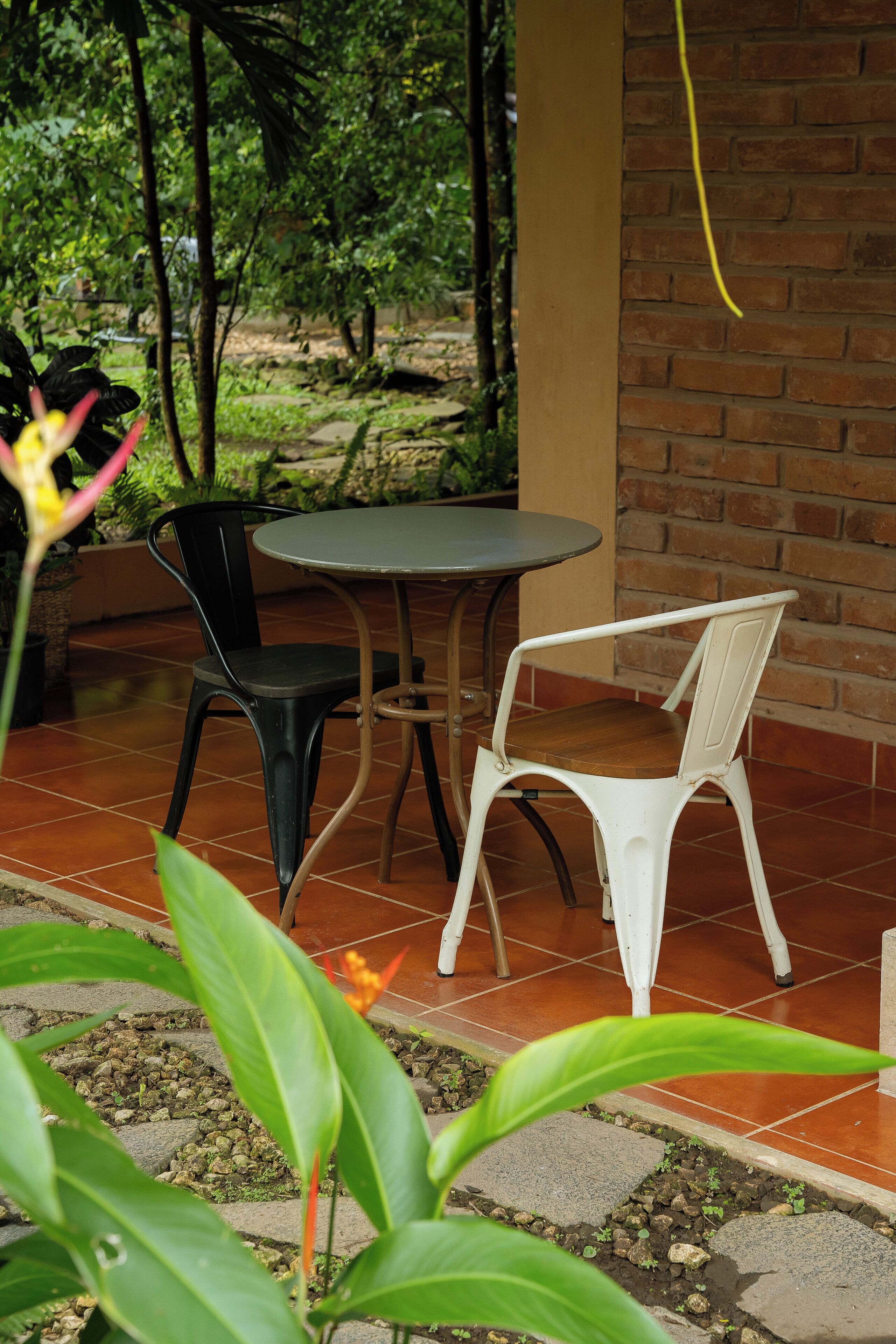 A patio with two chairs, a table, and a brick wall.