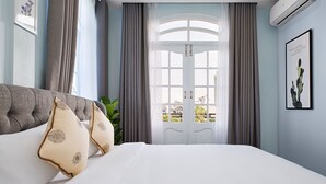 A bedroom with a large bed, a view through a glass door, and a framed picture on the wall. - The Mirror Danang Hostel (Da Nang)