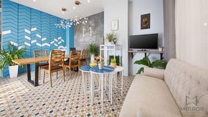 A modern hotel room with a dining area, a sofa, a TV, and a decorative wall. - The Mirror Danang Hostel (Da Nang)