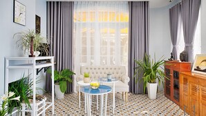 A room with a sofa, two tables, a cabinet, and various plants. - The Mirror Danang Hostel (Da Nang)