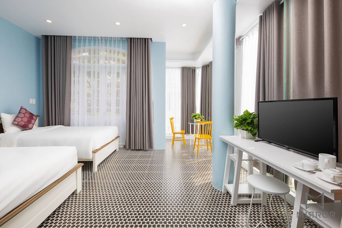 Una habitación de hotel con dos camas, un televisor, un escritorio con una silla y una mesita con una planta.
