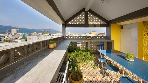 A rooftop terrace with a view of the city, a bar area with seating, and potted plants. - The Mirror Danang Hostel (Da Nang)