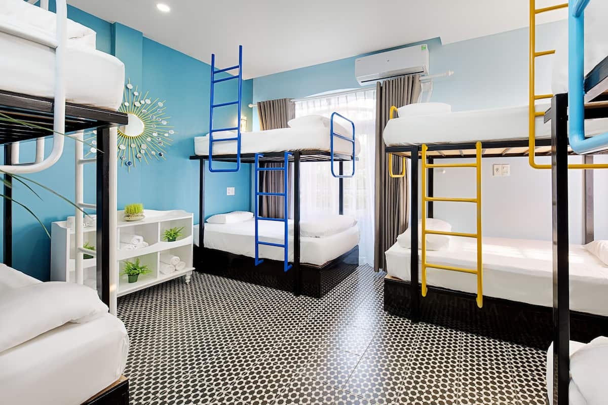 Dormitorio con literas, pared azul, techo blanco y suelo estampado.