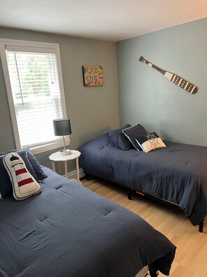 A bedroom with two beds, a window with blinds, a lamp, and a surf-themed artwork on the wall. - Walk to the Beach!!! (Centerville)