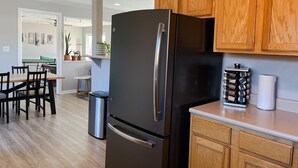 Een moderne keuken met houten kastjes, een koelkast van roestvrij staal en een eethoek met een pooltafel.