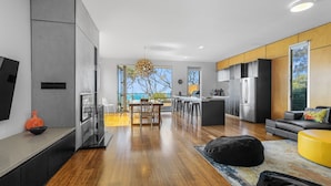Een moderne keuken met een centraal eiland, een eetgedeelte met uitzicht en een zithoek met een bank en voetenbankje.
