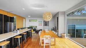 Een moderne keuken met een groot keukenblok, barkrukken en een grote hanglamp.