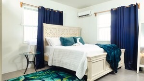 Une chambre à coucher avec un lit, une table de chevet, une lampe et une fenêtre avec des rideaux.