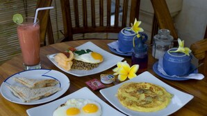 Una mesa con alimentos para el desayuno, incluyendo huevos fritos, arroz, tostadas y una bebida.