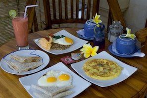 A table with breakfast items including fried eggs, rice, toast, and a drink.